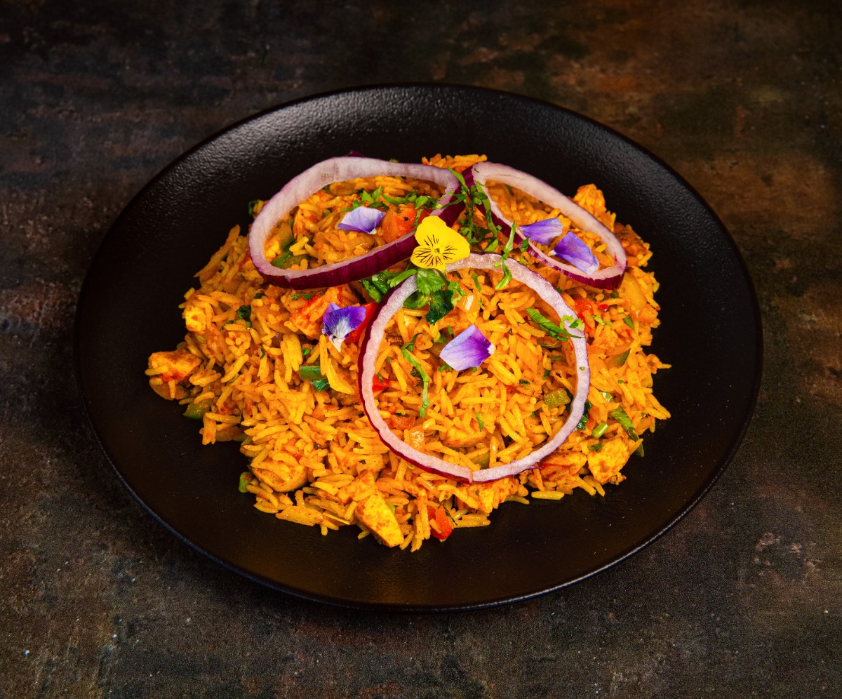 Rice dish on a dark place garnished with ring of onion and flower petals f