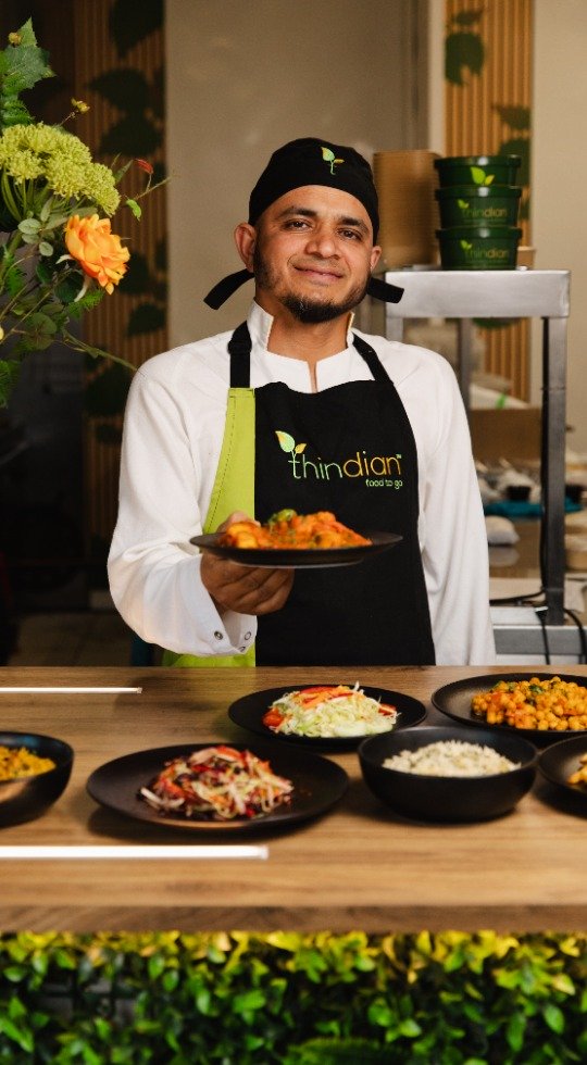 Chef with a Thindian logo on his apron with dishes
